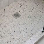 Terrazzo w brodziku prysznicowym z kwadratowym odpływem i szklaną kabiną
