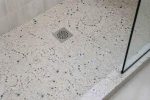 Terrazzo w brodziku prysznicowym z kwadratowym odpływem i szklaną kabiną