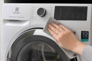 Dłoń przeciera ściereczką panel pralki Electrolux ładowanej od frontu